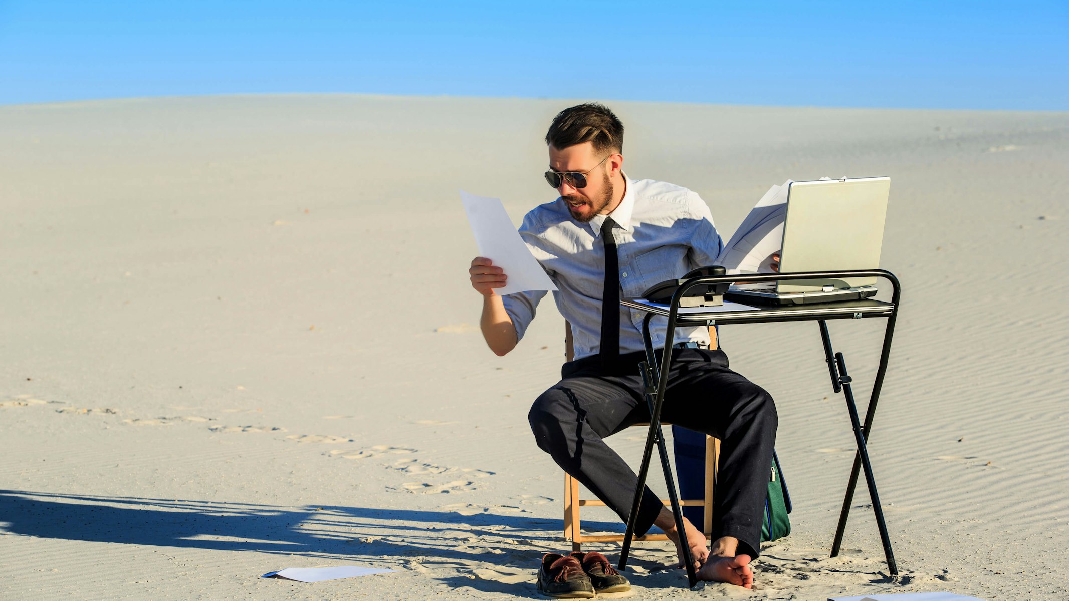 Man op laptop in de woestijn
